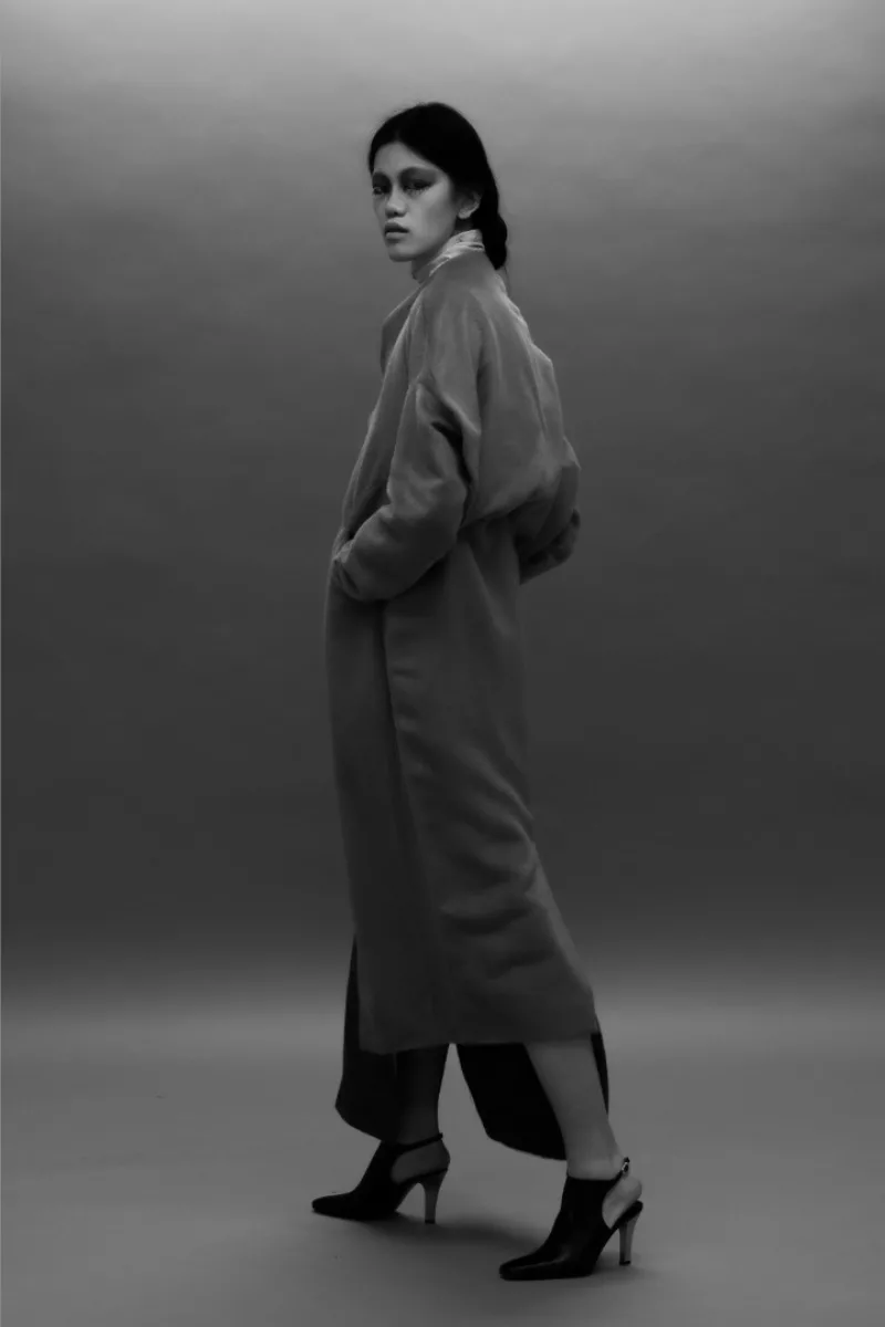 A model wearing a long coat looking over her shoulder at the camera very moody from Wenxin’s BFA thesis collection from Parsons fashion school
